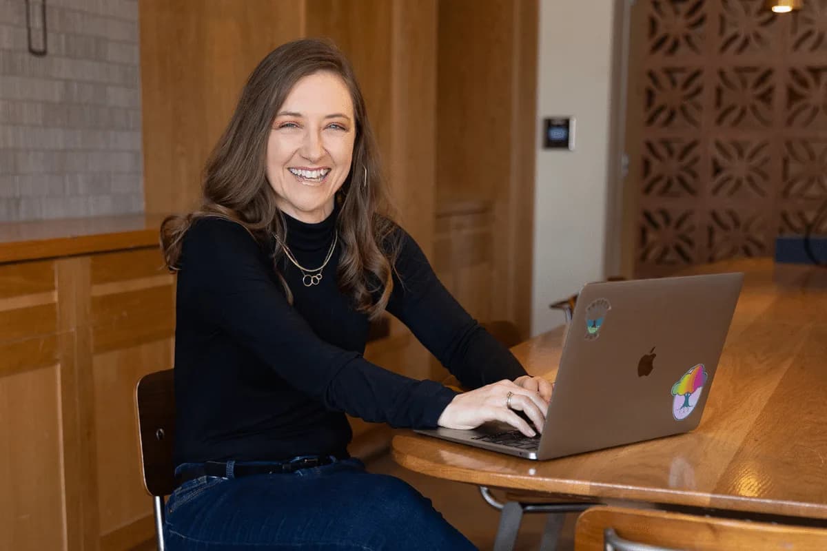 Smiling businesswoman working on a laptop at a wooden conference table